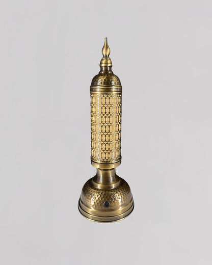Decorative brass lamp with intricate patterns on a light gray background