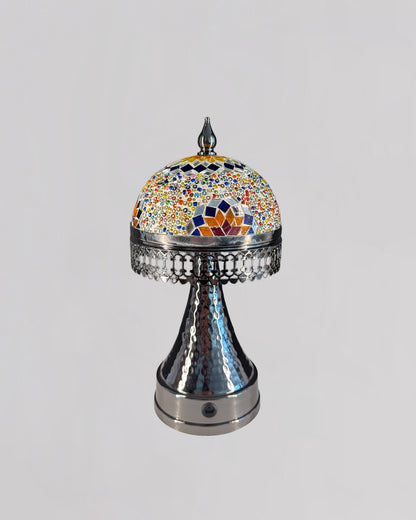 Decorative object with a colorful mosaic top and metallic base on a light gray background