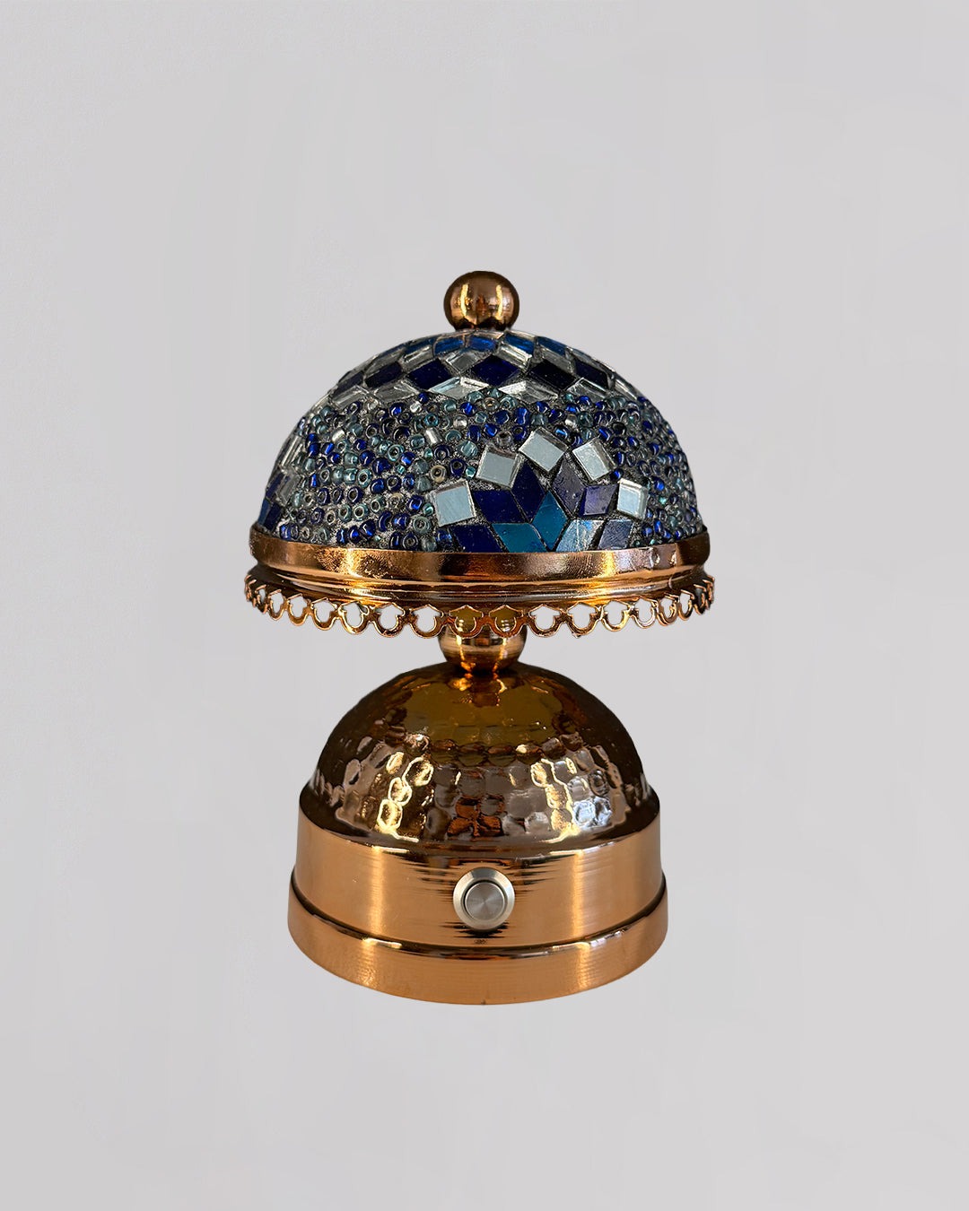 Decorative object with blue gemstones and gold accents on a gray background