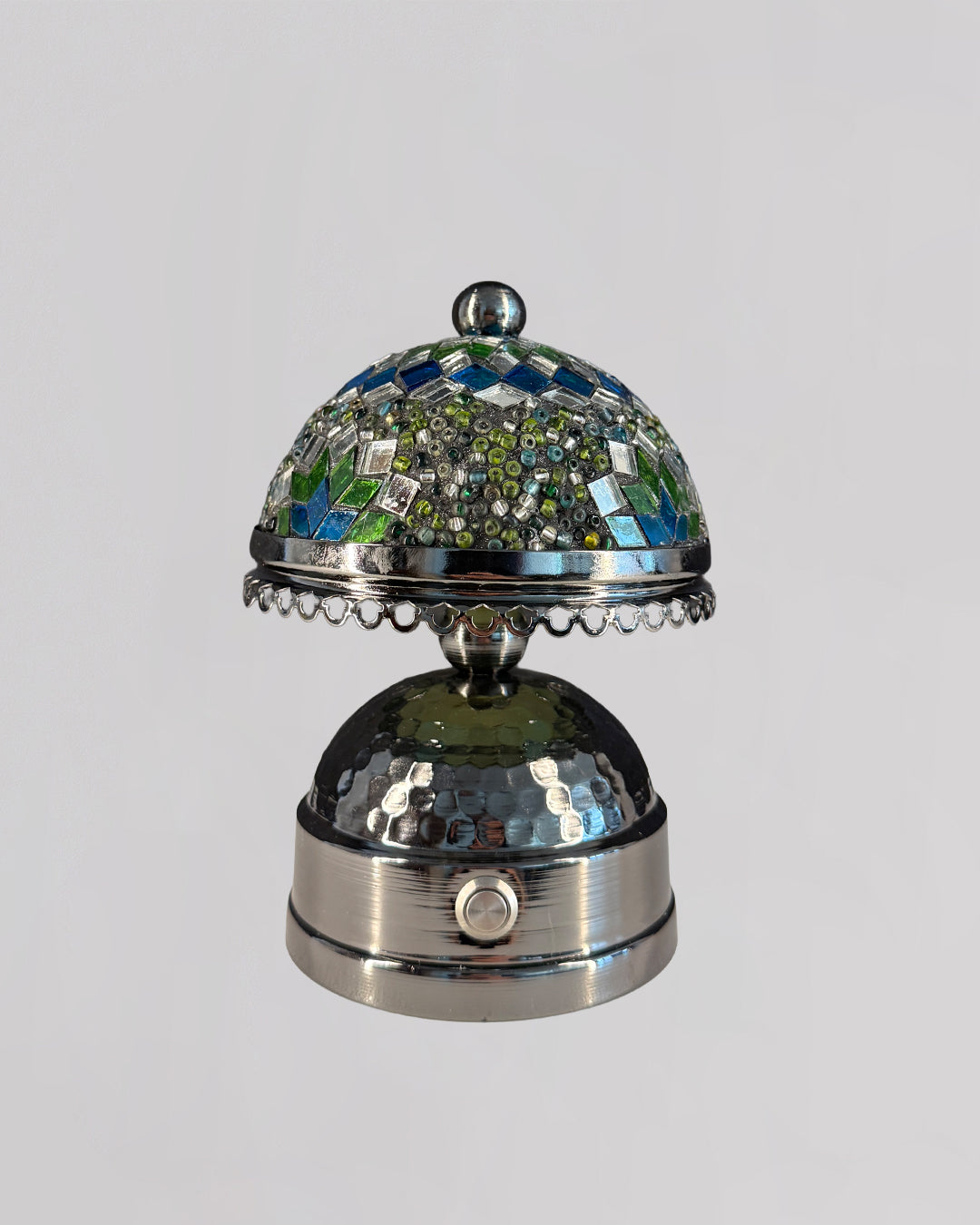 Decorative silver bell with mosaic top on a light gray background