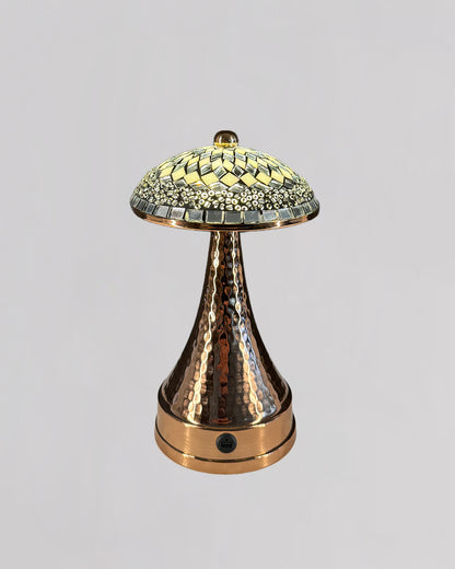 Decorative lamp with a textured bronze base and mosaic glass shade on a light gray background